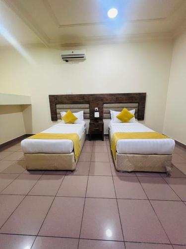 two beds with yellow pillows in a room at شقق نواميس للشقق المخدومة in Khamis Mushayt