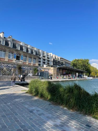 un bâtiment à côté d'une rivière avec des gens qui marchent sur un trottoir dans l'établissement Appartement Paris arrondissement 10, à Paris