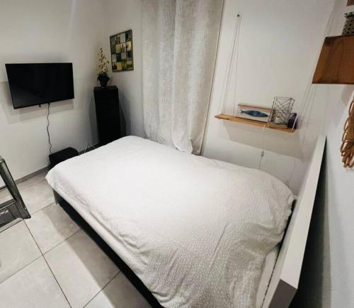 a bedroom with a white bed and a television at Studio cosy au cœur Panier in Marseille