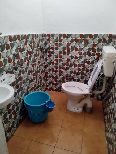 a bathroom with a toilet and a blue bucket at Corbett Green Orchard in Rāmnagar