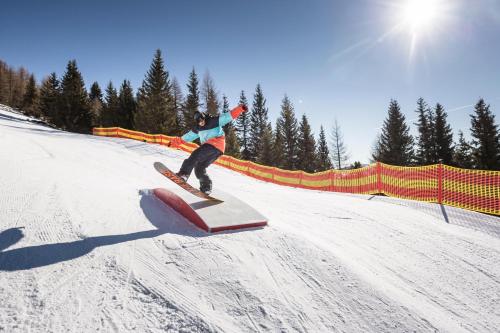 a person riding a snowboard on a rail in the snow at COOEE alpin Hotel Bad Kleinkirchheim in Bad Kleinkirchheim