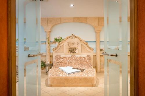 a glass door with a bed with a book on it at Wellnesshotel Waldruh in Bad Kohlgrub