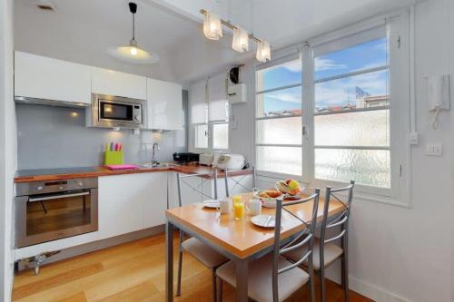 une cuisine avec une table et des chaises et une cuisine avec des armoires blanches dans l'établissement MyrAzur Carre d'Or, à Nice