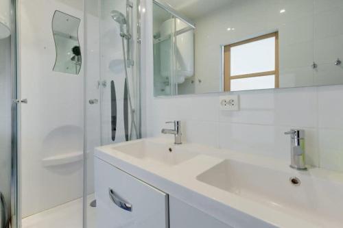 une salle de bain blanche avec un lavabo et une douche dans l'établissement MyrAzur Carre d'Or, à Nice