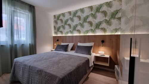 a bedroom with a large bed with a tropical wallpaper at Villas Punta Silo - luxury apartments with pool in Šilo