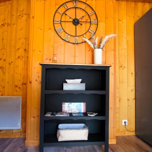 une étagère noire avec une horloge sur un mur en bois dans l'établissement T2 tout confort avec balcon au calme entre lac et montagne, à Brizon