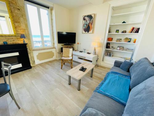 un salon avec un canapé bleu et une télévision dans l'établissement Hoya, Appt en front de mer avec jardin partagé, à Luc-sur-Mer