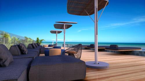 a deck with couches and chairs on the beach at Flat no New Time à beira-mar em Pajuçara Cama Queen in Maceió