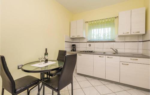 a kitchen with a table and chairs and a kitchen with white cabinets at Nice Apartment In Povljana With Wifi in Povljana