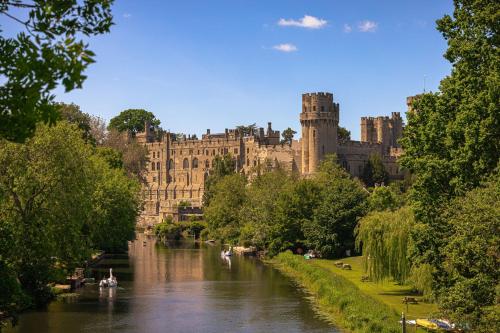 a large castle with a river in front of it at Furlong Barn in Southam