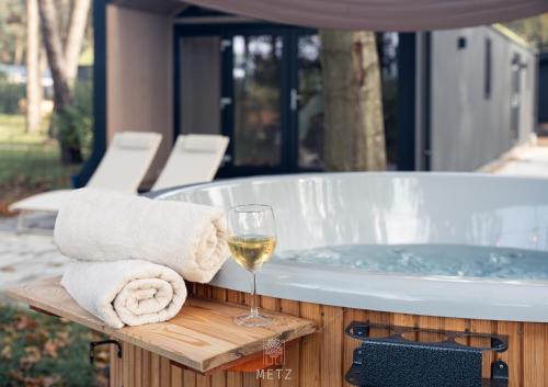 a glass of wine next to a tub with a glass of white wine at Sallands natuurhuisje Hellendoorn hottub Metz in Haarle