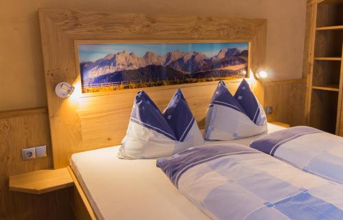 a bedroom with a bed with blue and white pillows at Pension Schweizerhof in Waidring