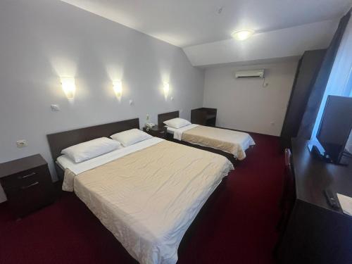 a hotel room with two beds and a television at Hotel Elegance in Belgrade