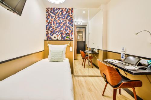 une chambre d'hôtel avec un lit, un bureau et un ordinateur dans l'établissement WS Opéra - Malesherbes, à Paris