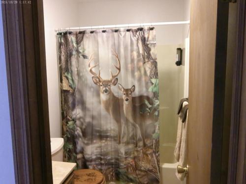a shower curtain with two deer in a bathroom at Serenity and Fun all in one in this Cozy Pocono Cabin in Jim Thorpe