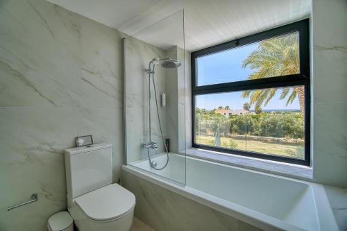 a bathroom with a shower and a toilet and a window at Luxury Oasis Villa in Peyia