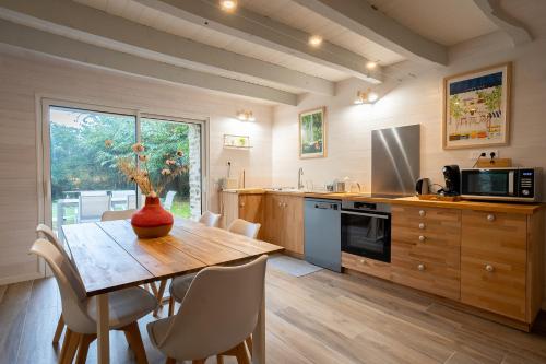 une cuisine avec une table en bois et des chaises ainsi qu'une salle à manger dans l'établissement Gîte Marguerite - Maison avec jardin de 3500m2, à Brandivy