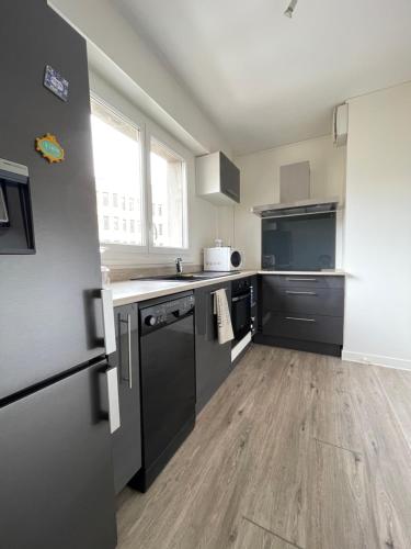 Il comprend une cuisine équipée d'appareils noirs et du parquet. dans l'établissement Appartement T4 Centre Ville C3, à Châteauroux