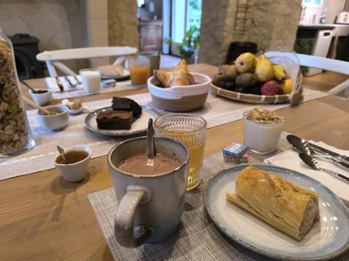 a table with a cup of coffee and a plate of bread at La Cale de la Clauderie in Rigny-Ussé