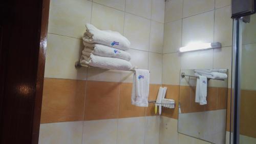 una pila de toallas en un estante del baño en 67 Airport Hotel Nairobi, en Nairobi