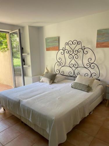 une chambre avec un grand lit blanc avec une grande tête de lit dans l'établissement figuier 2 - 1 chambre & piscine - 5 mn plage, à Zonza