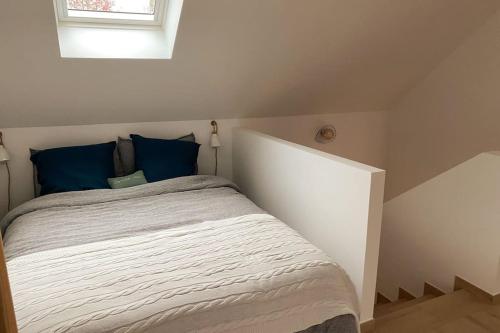 a bedroom with a bed with blue pillows and a window at La Grangerie - Maison en pierre centre village in Arbonne-la-Foret