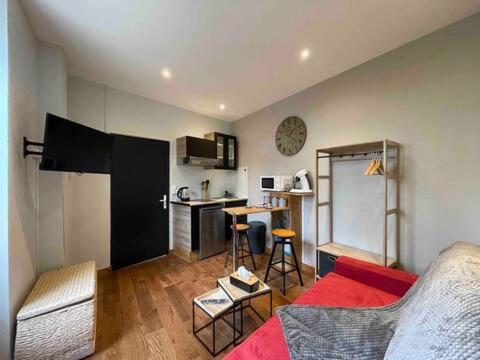 un salon avec un canapé rouge et une cuisine dans l'établissement Studio Confortable - Périgueux, à Périgueux