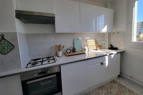 une cuisine blanche avec une cuisinière et un évier dans l'établissement Bright flat in Saint-Raphaël, à Saint-Raphaël