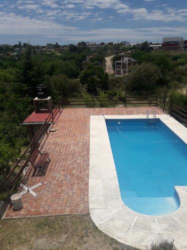 a swimming pool on a brick patio with a grill at Hermosa casa con pileta en estancia vieja carlos paz in Estancia Vieja