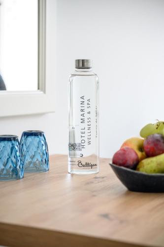 a bottle of water sitting on a table with a bowl of fruit at Hotel Marina in Port de Soller