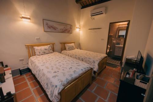 a small bedroom with two beds and a mirror at 新龍頭古厝行館 Shin Long Tou B&B in Jinning