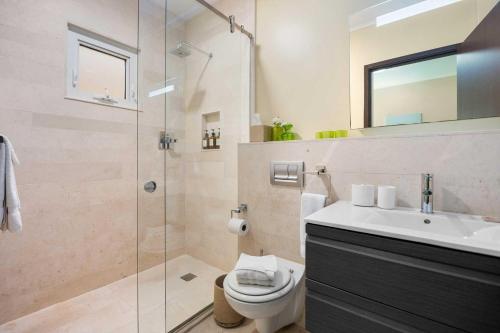 a bathroom with a shower and a toilet and a sink at Eagle Beach- Best 2BR rates at LeVent Resort-LV105 in Palm-Eagle Beach
