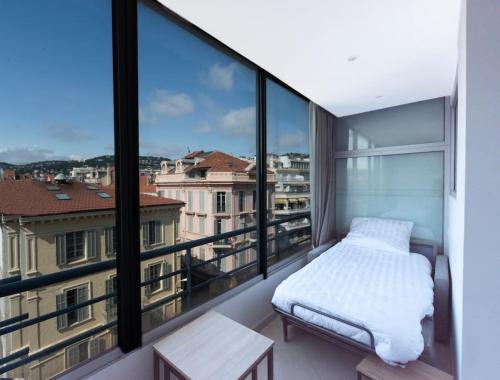 a bed on a balcony with a view of a city at Le Grand Hôtel -Centre Croisette in Cannes