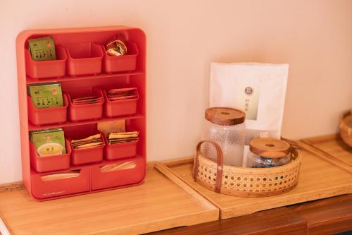 a red toy box sitting on a wooden table with a basket at 新龍頭古厝行館 Shin Long Tou B&B in Jinning