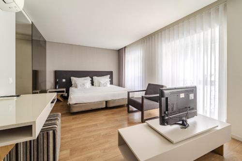 a hotel room with a bed and a desk with a television at Sé INN Studios by House and People in Braga