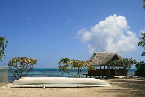 a surfboard laying on a beach next to a hut at Pension Motu Iti in Pihaena