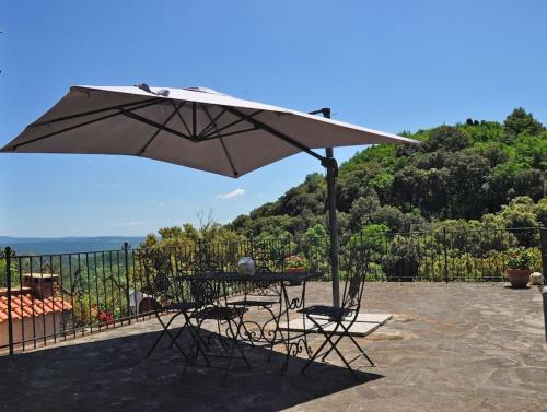 a table and chairs under an umbrella on a patio at Casa La Terrazza-Le Fornaci- in Sassetta