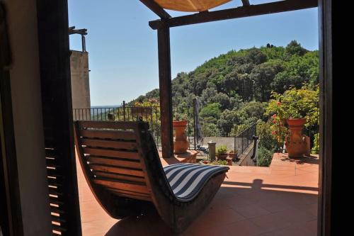 a rocking chair on a porch with a view of a mountain at Casa La Terrazza-Le Fornaci- in Sassetta