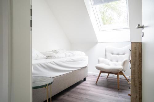 a bedroom with a bed and a chair and a window at Dünenquartier Apartment 30 in Zingst