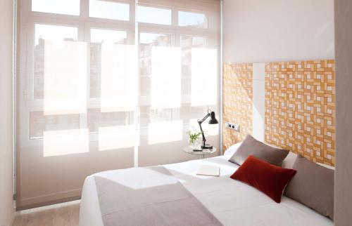 una camera da letto con un letto bianco e una grande finestra di Eric Vökel Boutique Apartments - Gran Vía Suites a Barcellona
