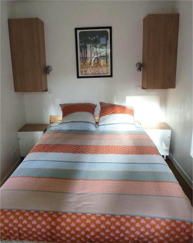 - une chambre avec un lit doté d'un couvre-lit rayé coloré dans l'établissement Au milieu des pins, charmant appartement de 38 m2 - 4 personnes - Domaine du Golf, à Lacanau-Océan
