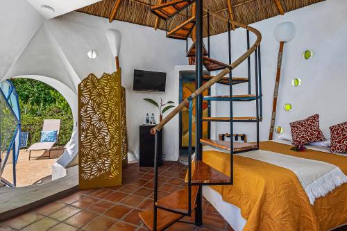 a bedroom with a bed and a spiral staircase at Villas Bambu in Barra de Navidad