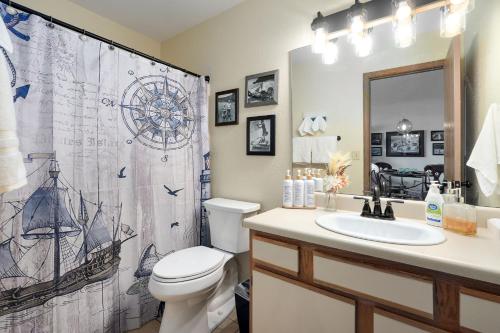 a bathroom with a shower curtain and a toilet and a sink at Captain's Quarters at Kimberling Crossing in Kimberling City