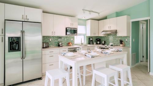 une cuisine avec des placards blancs et un îlot blanc avec des tabourets dans l'établissement Tidewater Views by Last Key Realty, à Cudjoe Key