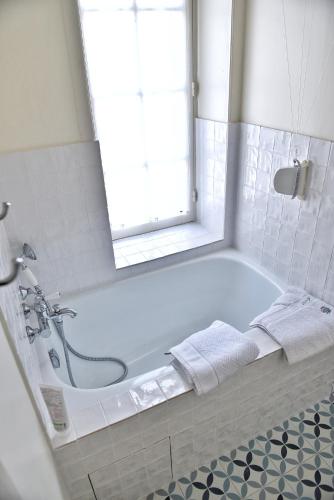La salle de bains blanche est pourvue d'une baignoire et d'une fenêtre. dans l'établissement Maison Henri Chardon, à Barfleur