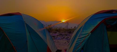 two tents on a beach with the sunset in the background at Mr. B's Place in Bhurkīā