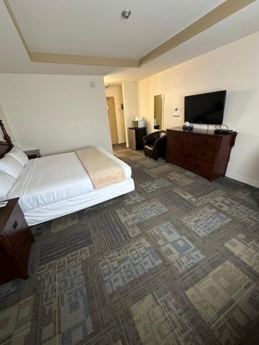 a hotel room with a bed and a flat screen tv at Sleep Suite Motel in Steinbach