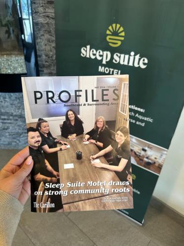a person holding a magazine with a picture of a group of people at Sleep Suite Motel in Steinbach