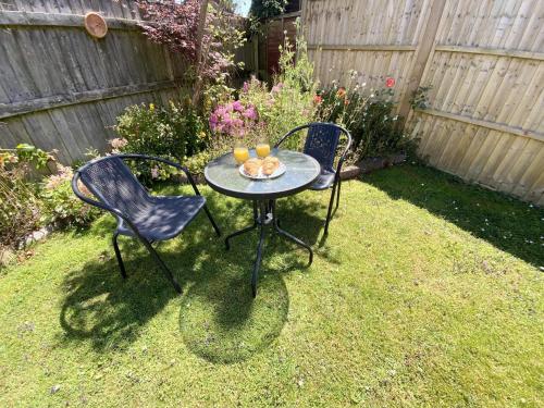 two chairs and a table with drinks on it in a yard at Daisy Cottage in Lymington