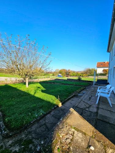 un banc blanc assis à côté d'une cour avec un arbre dans l'établissement Maison individuelle Idéale 10 pers !, à Échenoz-la-Méline